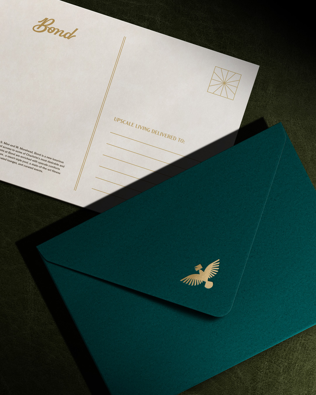 Dark teal envelope and postcard with a gold homing pigeon on the flap.